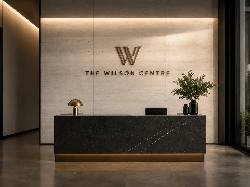 Lobby reception desk in front of a stone wall with The Wilson Centre logo